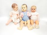 three dolls sitting next to each other on a white surface