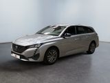 La voiture argentée est garée dans une pièce blanche au sol noir.