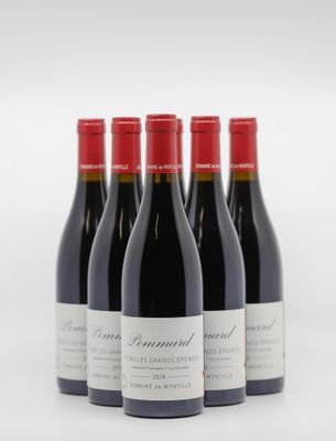 quatre bouteilles de vin rouge sont alignées sur une surface blanche