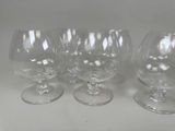 four empty wine glasses are lined up on a white surface