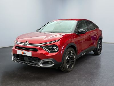 La voiture rouge est garée dans une pièce au sol noir.