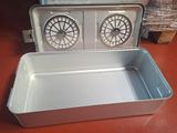 a metal pan with two fan ' s in it on a table