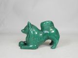 a small green statue of a dog on a white surface