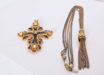 a close up of a cross and a tassel on a white surface