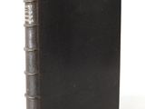 an old black book sitting on top of a table next to a white background