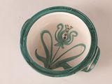 a green and white vase with a flower on it