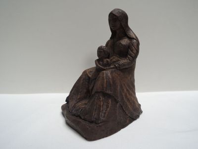 statue représentant une femme assise sur un rocher, tenant un bébé dans ses bras