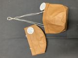 deux sacs en papier kraft avec des étiquettes accrochées dessus, posés sur une surface noire