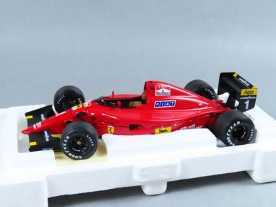 une maquette de voiture de course rouge posée sur un socle blanc