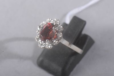 une image d'une bague avec une pierre rouge entourée de diamants blancs