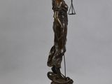 a bronze statue of a lady holding a scales on a pedestal