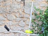 a small pole with a yellow handle next to a bush