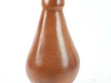 a brown vase with a cork top on a white surface
