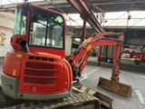 a red excavator that is parked inside of a building