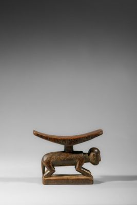 une sculpture en bois représentant un chien et un oiseau, posée sur un socle