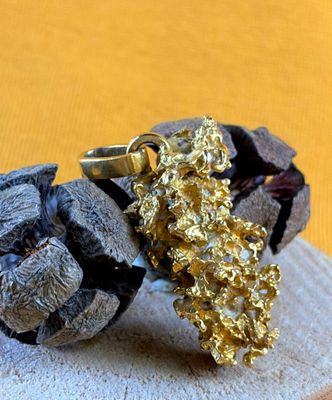 gold nugget on a piece of wood with a gold nugget on top