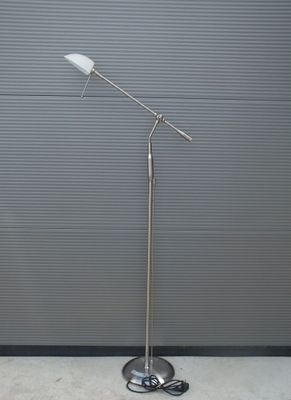 un lampadaire argenté surmonté d'un abat-jour blanc