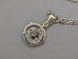 un gros plan sur un collier en argent orné d'une horloge