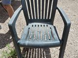 a green plastic chair that is sitting in the dirt