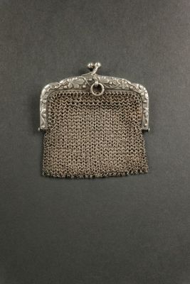 un porte-monnaie en argent muni d'une chaîne, posé sur une table