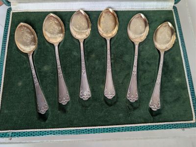 five spoons in a box on a green surface