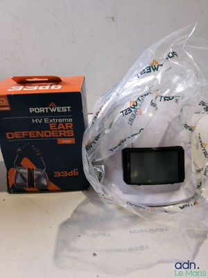 une petite horloge numérique dans un sac en plastique, à côté d'une boîte
