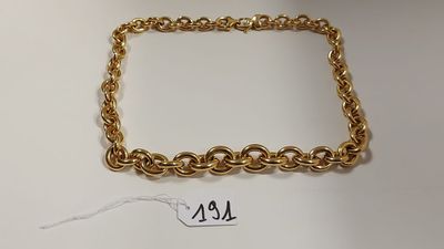 gros plan d'un bracelet en chaîne en or sur une surface blanche