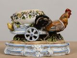 a figurine of a rooster pulling a cart with eggs on it