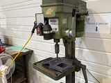 une perceuse posée sur une table dans un atelier où se trouvent de nombreux outils