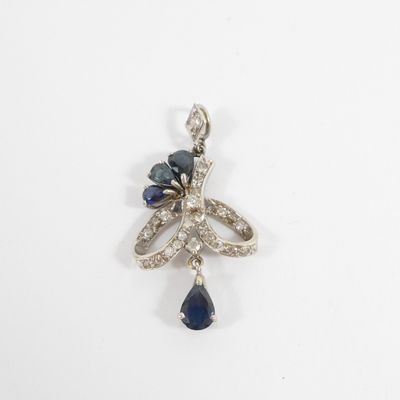 a close up of a blue and white diamond pendant on a white surface