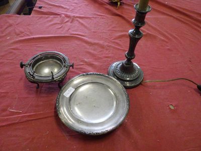 a silver plate on a table with a candle and a silver plate on the table