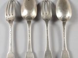 quatre cuillères en argent et une fourchette sont alignées sur une surface blanche