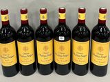 six bottles of red wine lined up in a row on a table