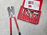 une boîte à outils rouge contenant des outils et une paire de pinces, posée par terre