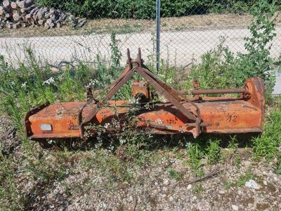 une charrue orange rouillée posée dans l'herbe