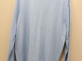 a light blue sweater hanging on a hanger against a wall