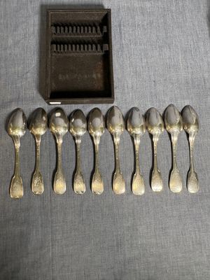 six cuillères en argent et une boîte contenant une brosse à dents, posées sur une table