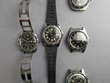 four watches and a watch bracelet on a table