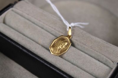un collier en or sur lequel est gravée l'image d'une femme