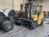 a forklift that is parked next to a pile of rolls of paper