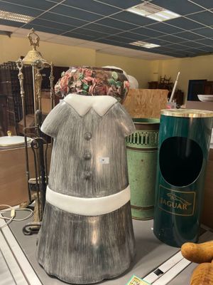 une statue représentant une femme en robe et un ours en peluche posés sur une table