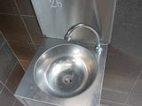 a stainless steel sink in the corner of a public restroom