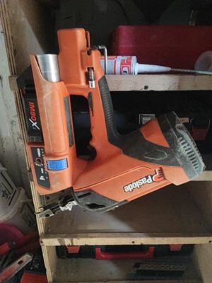 une agrafeuse sans fil orange posée sur une étagère en bois