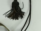 a necklace with a tassel hanging from it on a white surface