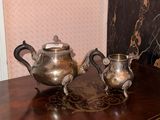 two silver teapots sitting on a table next to each other