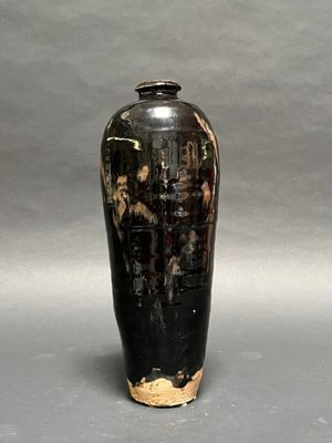 a black and gold vase sitting on a gray surface