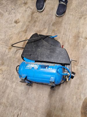 un compresseur d'air bleu posé par terre à côté d'une paire de chaussures