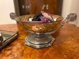 a glass bowl on a wooden table with silver spoons on it