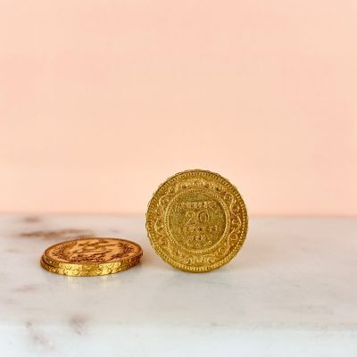 two gold coins sitting on top of a marble counter top