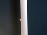 a white floor lamp on a wooden floor next to a black wall